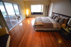 Ein Schlafzimmer mit einem großen Bett, einer Sitzbank am Fenster und Blick auf einen Balkon.