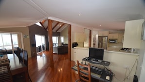 A spacious kitchen with modern appliances, a dining area with wooden furniture, and a view of the outdoors. - The White House (Norfolk Island)
