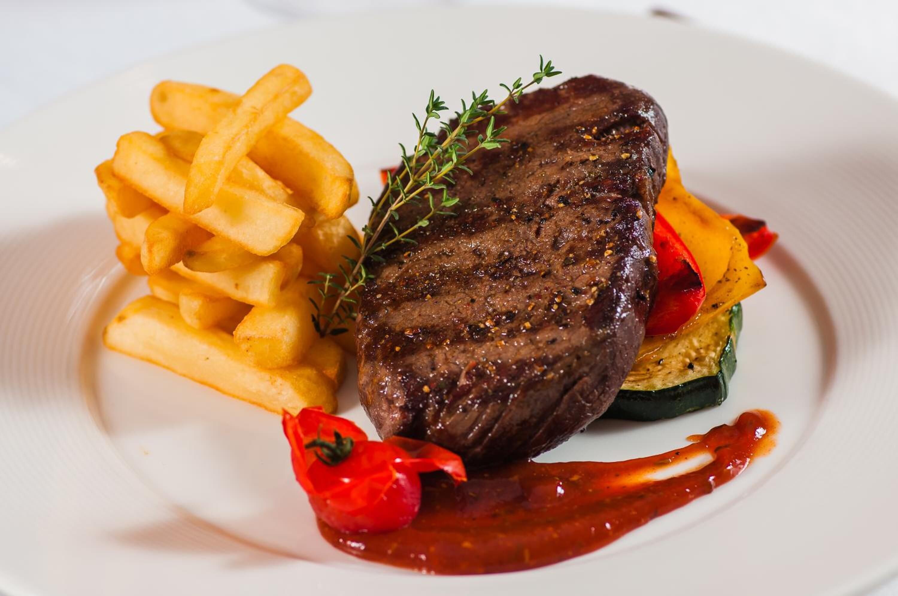 Un piatto con una bistecca, patatine fritte e verdure.