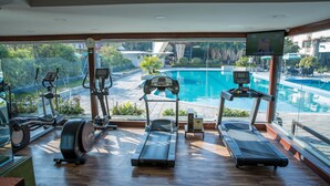 A gym with treadmills, elliptical machines, and a rowing machine, overlooking a swimming pool. - Hotel Annapurna (Kathmandu)
