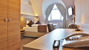 Una habitación de hotel moderna con una cama, una mesita de noche y un escritorio con un teléfono y gafas.