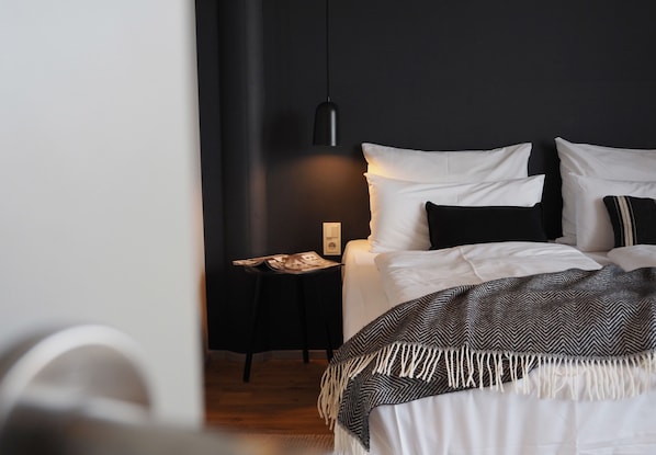 A bedroom with a bed, a bedside table, a lamp, and a wall-mounted light fixture.