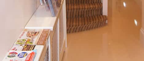 Eine Treppe mit gemustertem Teppich, einem Wandspiegel und einem Zeitschriftenständer.
