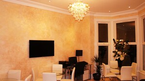 Un salon moderne doté d’un téléviseur à écran plat, d’un lustre et d’une grande fenêtre offrant une vue dégagée.