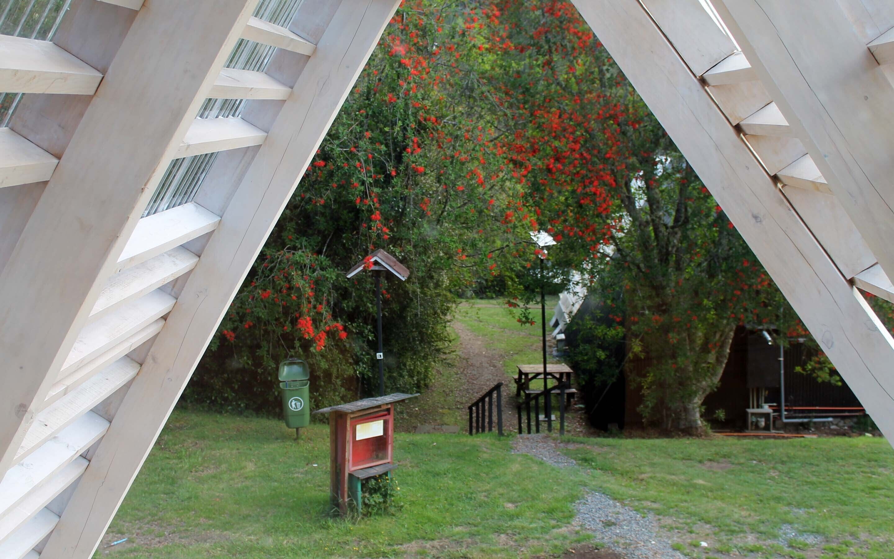 Una estructura de madera con una escalera que lleva a un espacio cubierto con un banco y un cobertizo pequeño.