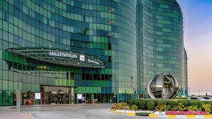 A modern building with a curved glass facade and a prominent spherical sculpture in front.