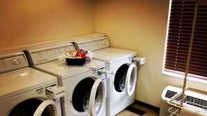 Une buanderie équipée de deux machines à laver et deux sèche-linge à chargement frontal, d’un panier de lessive et d’un sèche-linge à évacuation.