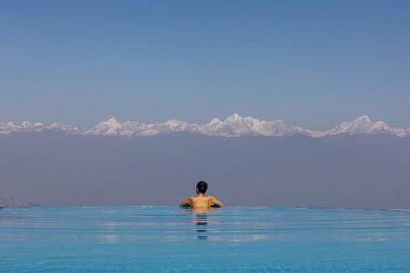 Une personne dans une piscine, avec une chaîne de montagnes en arrière-plan.