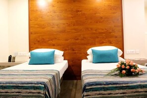Habitación de hotel con dos camas, cada una con una colcha a rayas y una almohada azul.