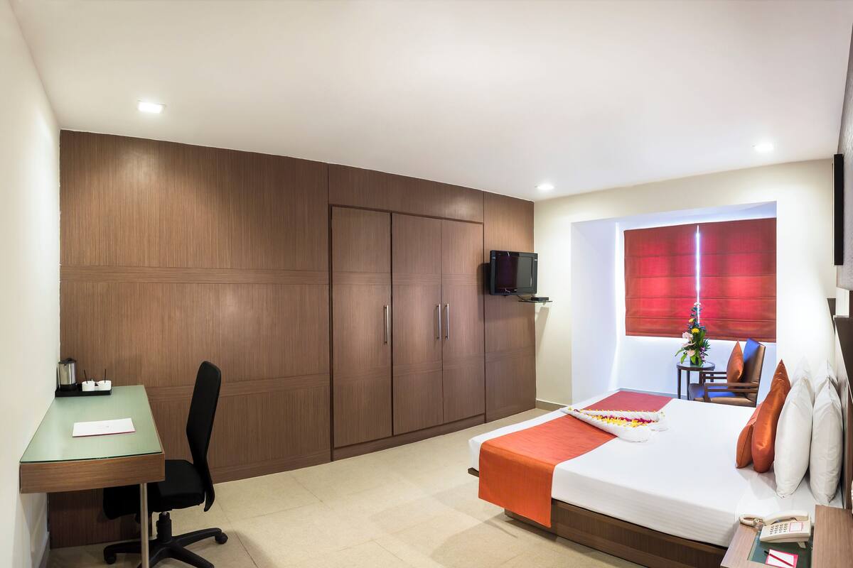 Ein Hotelzimmer mit Bett, Schreibtisch, Stuhl, Kleiderschrank und Fernseher.