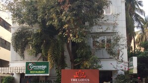 Un immeuble sur lequel on peut lire les enseignes « Greenways, restaurant gastronomique » et « The Lotus, appartements-hôtels ».