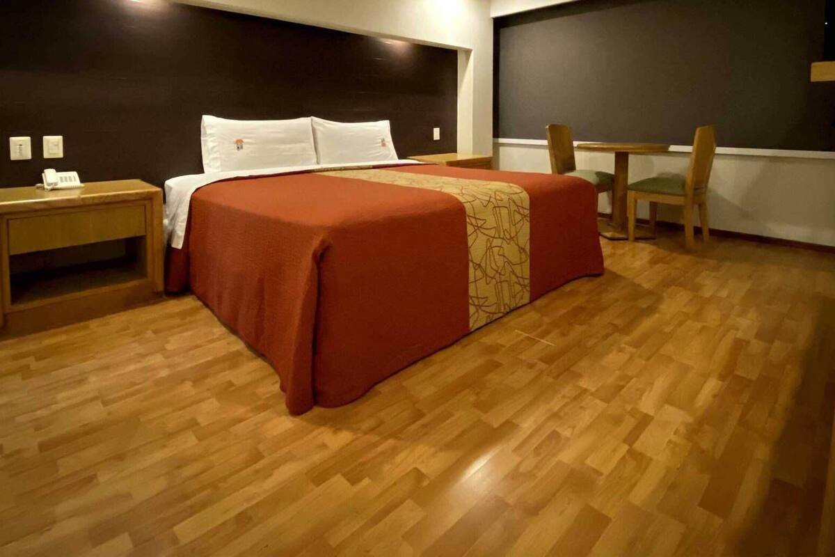 Une chambre d’hôtel comprenant un lit, des tables de chevet, un bureau et une chaise.