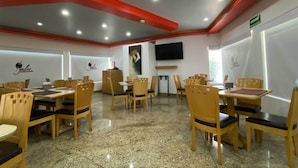 A restaurant with wooden tables and chairs, a flat-screen TV mounted on the wall, and a red ceiling. - Hotel Lord - Adults Only (Mexico City)