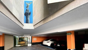 A parking garage with a statue, a reception area, and a blue emergency exit sign. - Hotel Lord - Adults Only (Mexico City)