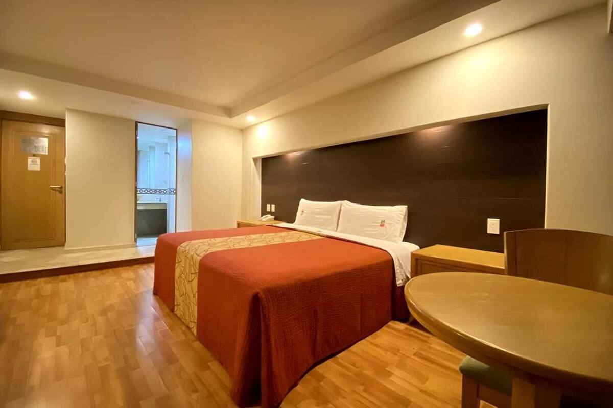Une chambre d’hôtel avec un lit, une table en bois et une vue sur l’extérieur.