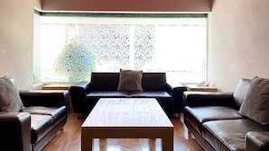 A living room with a brown leather sofa set, a wooden coffee table, and a patterned window blind. - Hotel Lord - Adults Only (Mexico City)