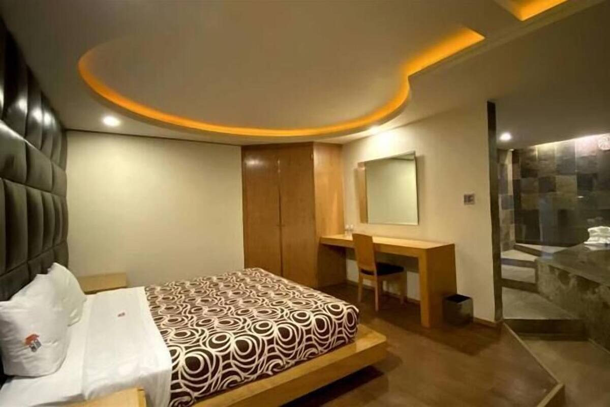 Une chambre moderne avec un lit, une coiffeuse et un espace douche.