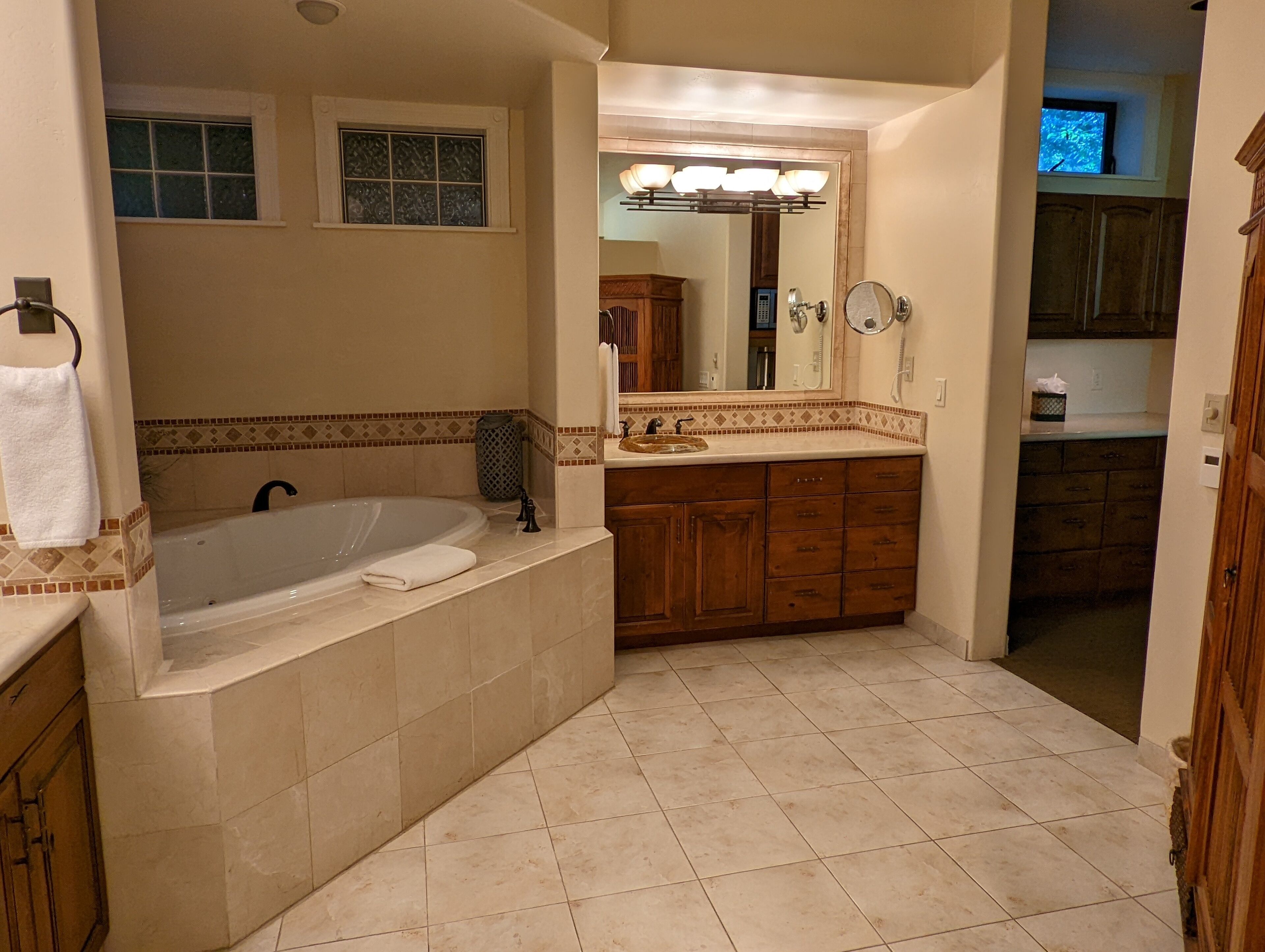 A bathroom with a large bathtub, wooden cabinets, and a vanity with a mirror.