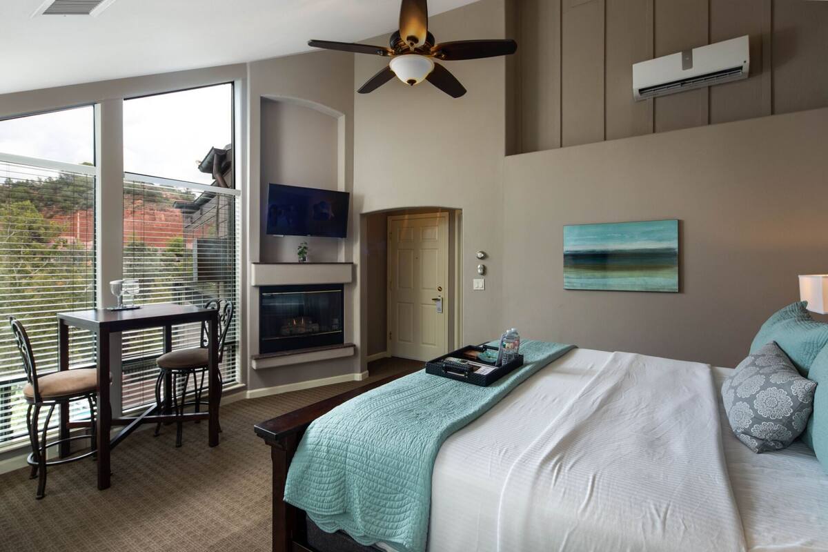 A bedroom with a bed, a TV, a fireplace, and a balcony.