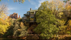 Un immeuble à plusieurs étages doté de balcons, entouré d’une végétation luxuriante et d’un paysage rocheux.