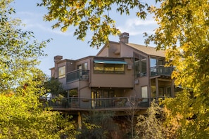 A multi-story house with a balcony on the ground floor, surrounded by trees. - The Inn Above Oak Creek (Sedona)