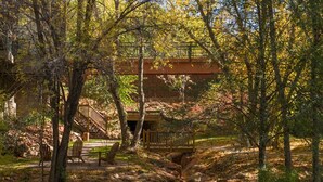 Un espace extérieur rustique agrémenté d’un pont en bois, d’un banc en pierre et d’une terrasse en bois.