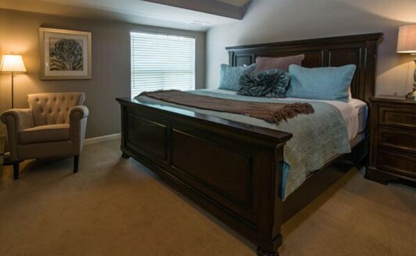 A bedroom with a large bed, a chair, a nightstand, and a window with blinds. - The Inn Above Oak Creek (Sedona)
