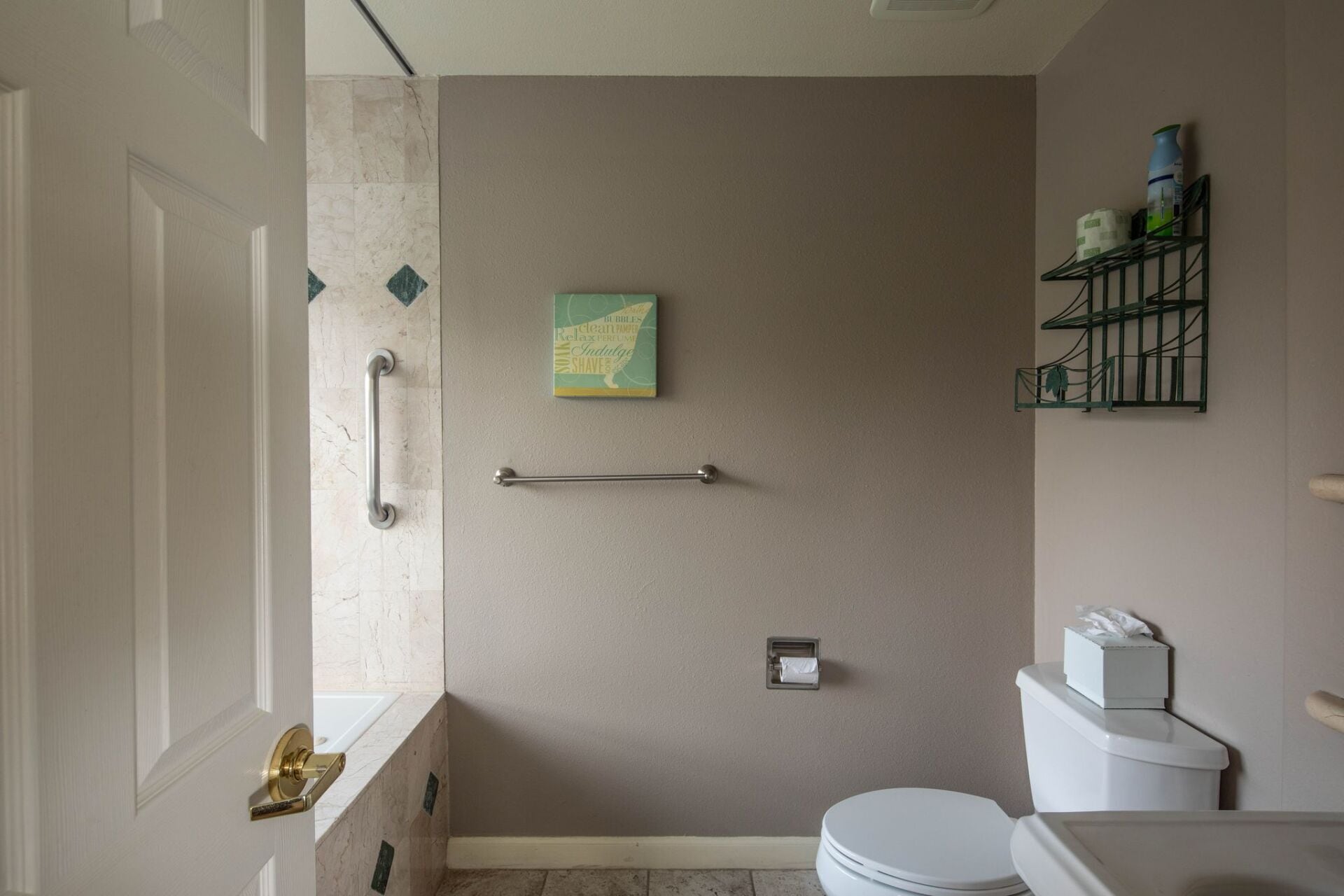 A bathroom with a toilet, a towel rack, a shelf with toiletries, and a door with a handle.