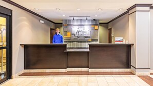 A hotel reception area with a modern design, featuring a reception desk, a digital display, and a tiled floor.