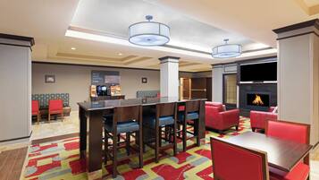 A hotel lobby with a bar area, seating, and a fireplace.