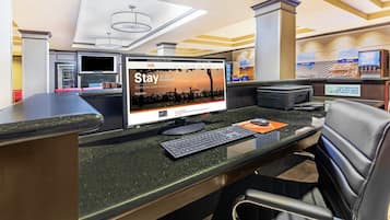 A reception desk with a computer monitor displaying a promotional screen, a telephone, and a fax machine.