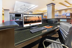 A reception desk with a computer monitor displaying a promotional screen, a telephone, and a fax machine.