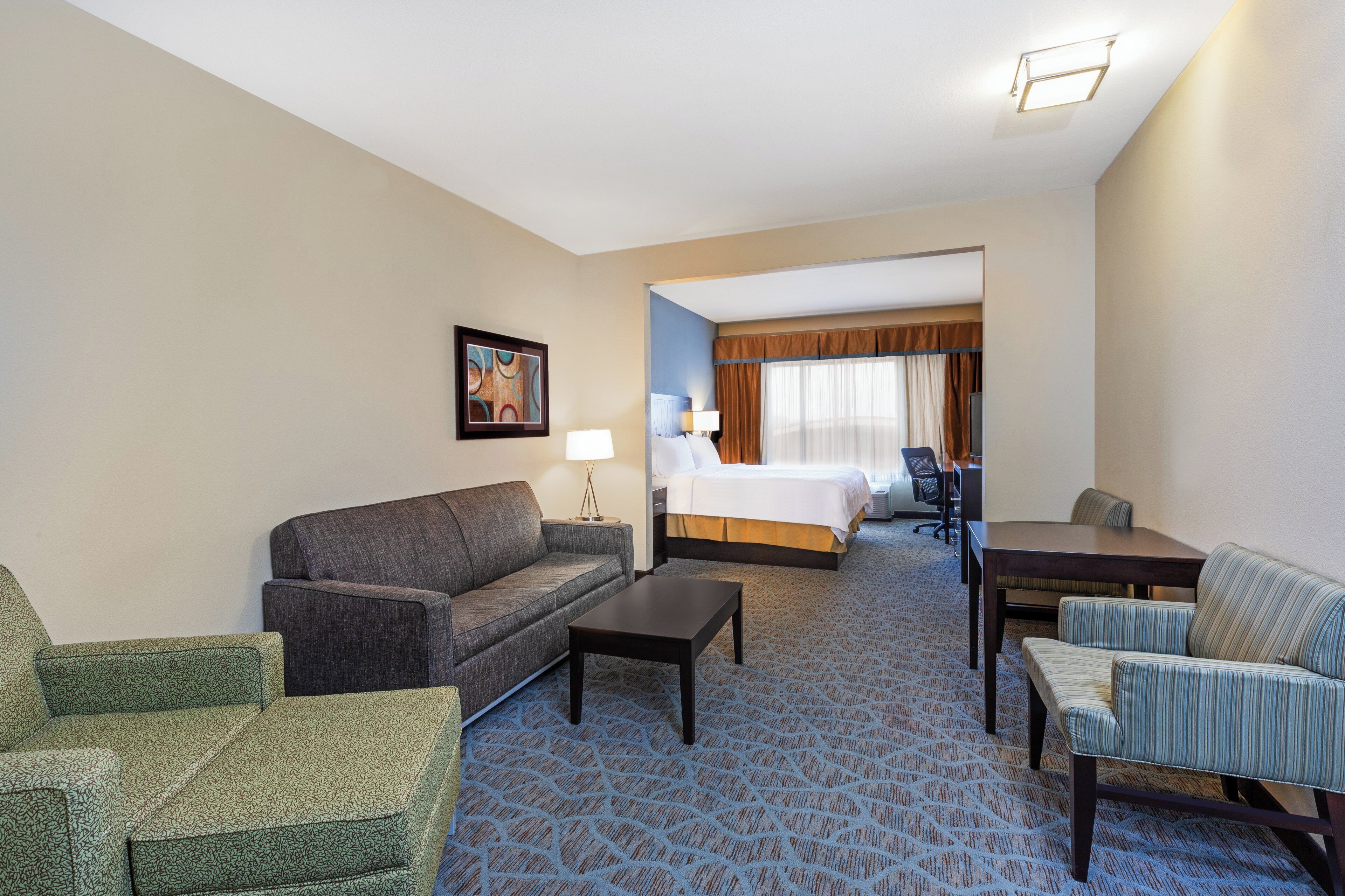 Una habitación de hotel con sofá, mesa de centro, mesa de comedor y cama.