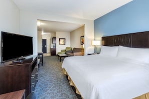 Quarto de hotel com uma cama grande, televisão de tela plana, escrivaninha e uma cadeira.