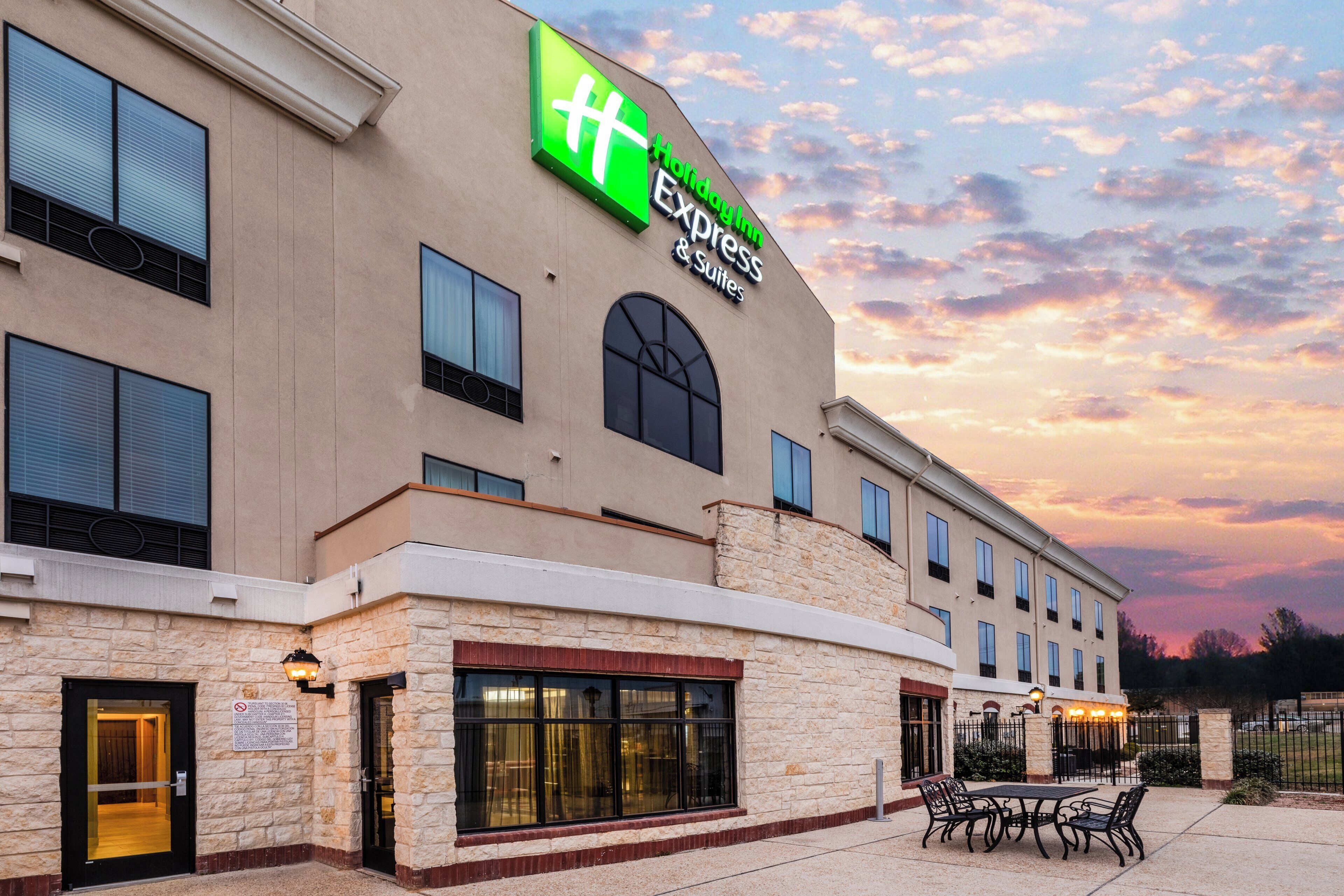 A hotel with a large sign for Holiday Inn Express & Suites, featuring a stone facade and multiple windows.