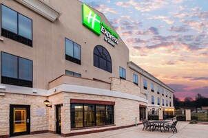 A hotel with a large sign for Holiday Inn Express & Suites, featuring a stone facade and multiple windows.