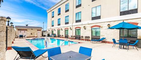 Una piscina al aire libre, sombrillas, sillones reclinables de piscina