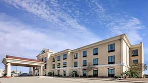 Un hotel con un ingresso coperto, diverse finestre e un cielo sereno.
