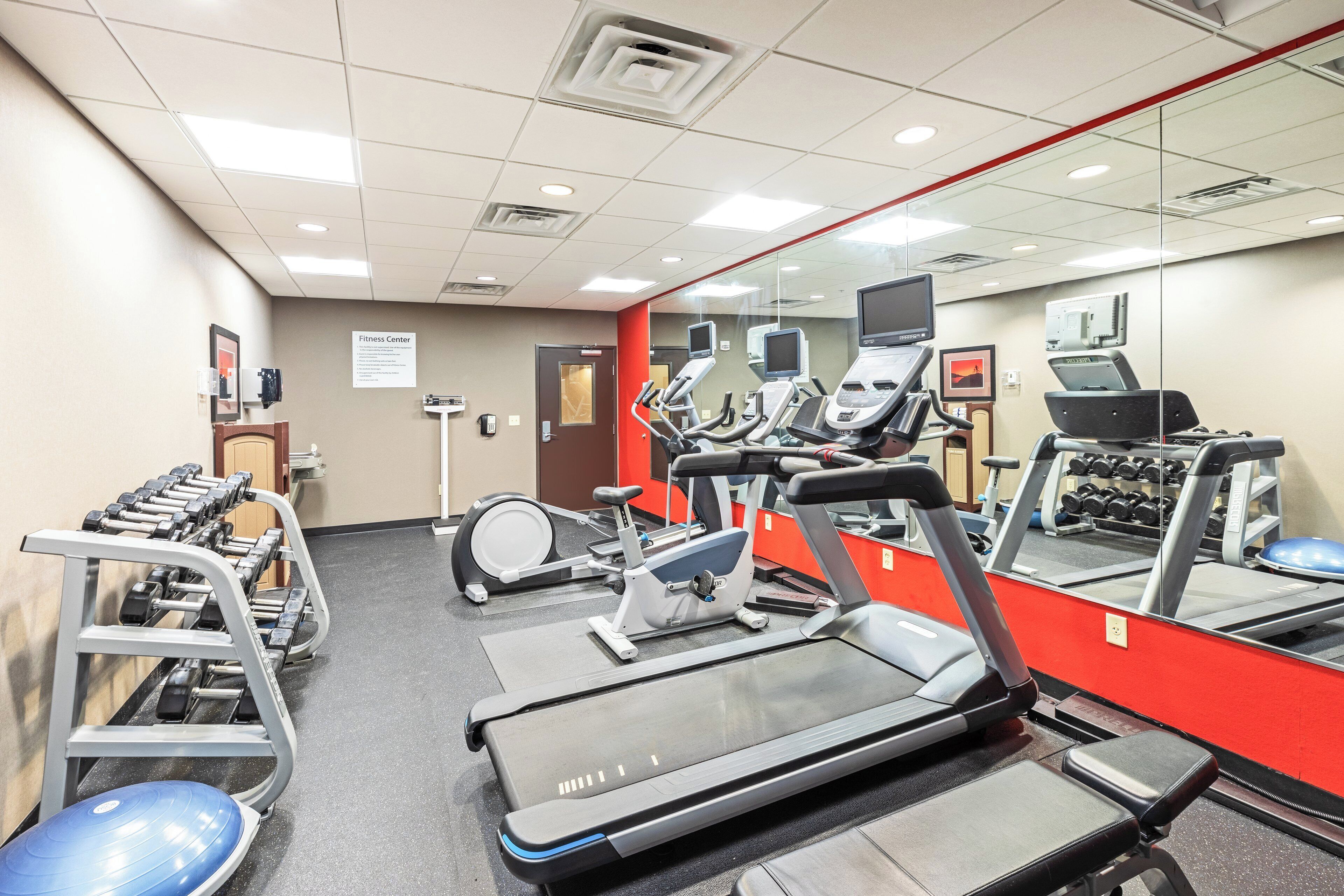 A fitness center with treadmills, elliptical machines, and a weight rack.