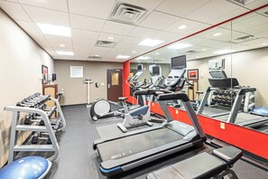 Un centre de remise en forme équipé de tapis de course, de vélos elliptiques et d’un banc de musculation.