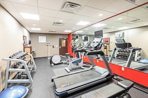 Un gimnasio con cintas de correr, elípticas y un soporte para pesas.