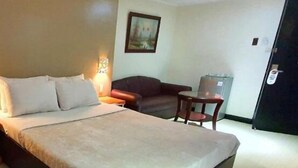 Une chambre d’hôtel équipée d’un lit, d’un bureau, d’une chaise, d’une lampe et d’un réfrigérateur.