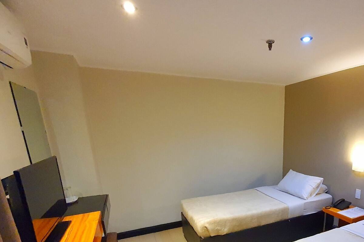 A hotel room with two beds, a desk, and a TV.
