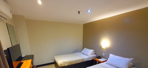 Habitación de hotel con dos camas, un escritorio y una televisión.