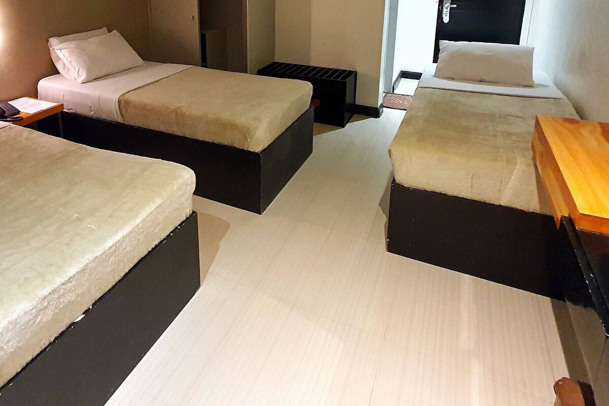 A hotel room with two beds, a wooden desk, and a television.