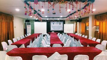 Un salón de conferencias con mesas rojas y sillas blancas, decorado con adornos colgantes.