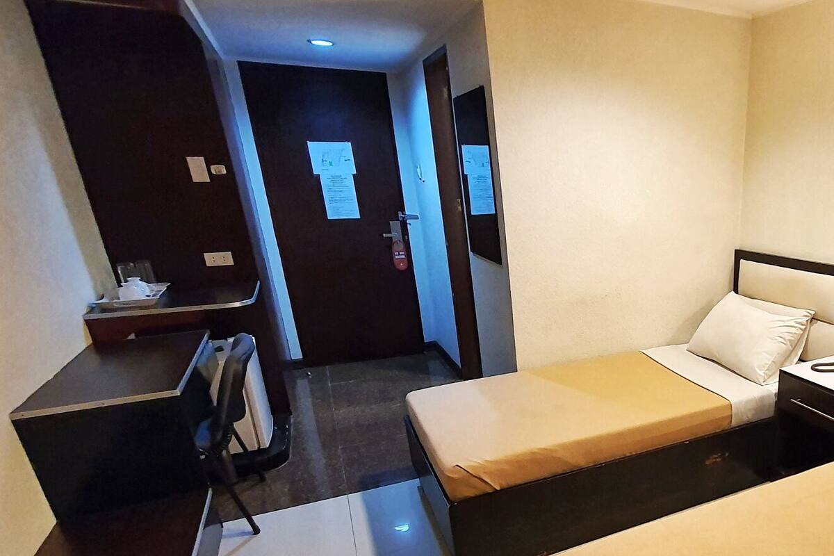 A hotel room with two beds, a desk, and a chair.