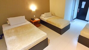 Une chambre d’hôtel avec deux lits, une table de chevet, une lampe fixée au mur et une porte équipée d’un détecteur d’incendie.