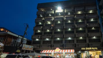 A multi-story hotel with balconies, a neon sign, and a visible restaurant sign.