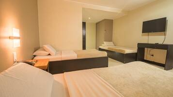 A hotel room with two beds, a desk, a TV, and a mirror.